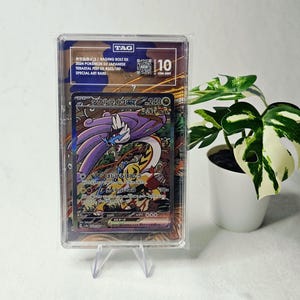 May include: A graded Raging Bolt ex Pokémon trading card in a clear protective slab with a TAG 10 Gem Mint label. The card features Japanese text, a 240 HP value, and colorful artwork of the creature. The slab is displayed on a clear stand.