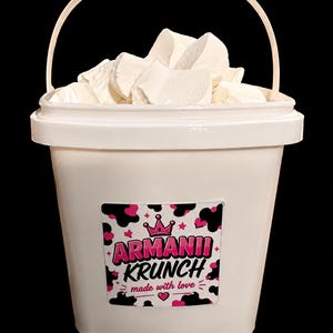 May include: A white bucket filled with white, irregularly shaped pieces. The bucket has a handle and a label with the text "Armanii Krunch" in pink and white, with a crown and the words "made with love."