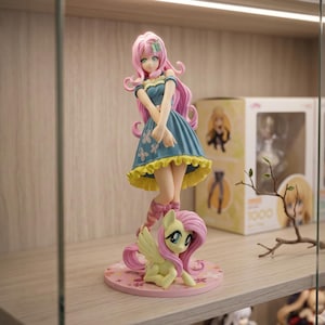 Op de afbeelding: Een verzamelbaar anime-figuurtje van een personage met lang roze haar in een blauwe jurk met een gele geplooide zoom en vlinderpatronen, staand naast een klein geel ponyfiguurtje met roze haar op een ronde, bloemrijke voet.