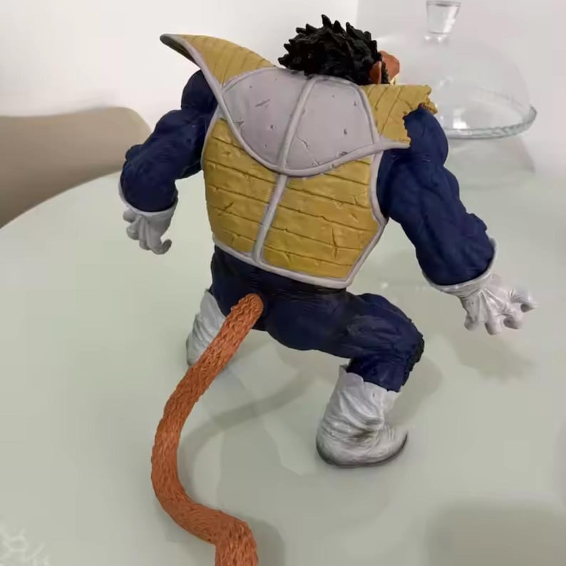 May include: A detailed action figure of a character in a fighting stance. The figure is primarily blue, with yellow and white armour. It has a long, orange tail and white gloves and boots. The figure's hair is black.