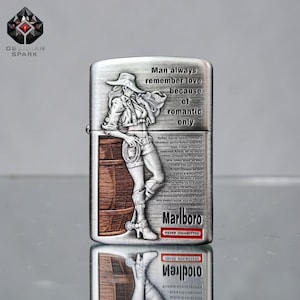 May include: Silver-colored metal lighter with a detailed engraving of a woman in a cowboy hat and shorts, leaning against a barrel. The lighter has the text "Man always remember love because of romantic only" and "Marlboro Filter Cigarettes".