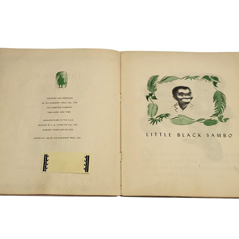 May include: Open book with the title page of "Little Black Sambo". The illustration features a black and white image of a person's face surrounded by green leaves. The text "Little Black Sambo" is below the image.