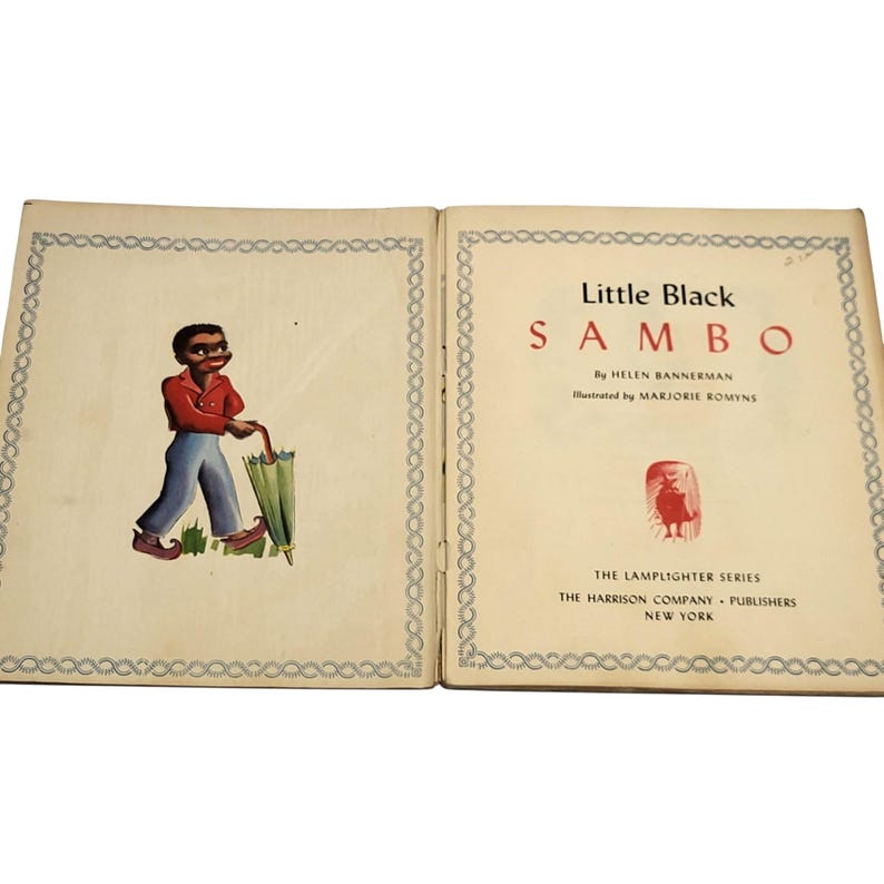 May include: Open book titled "Little Black Sambo" by Helen Bannerman, illustrated by Marjorie Romyns. The left page shows a cartoon figure in a red shirt, blue pants, and holding a green umbrella. The right page displays the title and publisher information.