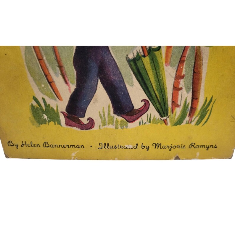 May include: Illustration of a person's legs in blue pants and red shoes with curled toes, holding a green and yellow umbrella. Carrots and grass are in the background. Text at the bottom reads "By Helen Bannerman - Illustrated by Marjorie Romyns."
