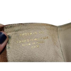 K&ouml;nnte beinhalten: Nahaufnahme des Inneren eines braunen Lederschuhs. Goldener Text lautet "PHOENIX 181", "773030-1401-804", "MADE IN BRAZIL" und "7 1/2 M". Das Innere des Schuhs ist hellbeige.