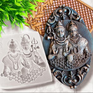 May include: A detailed, two-piece religious art set. One piece is a white silicone mold with a relief of two figures. The other is a finished, oval-shaped wall hanging with a blue and bronze finish, depicting two figures with ornate details.