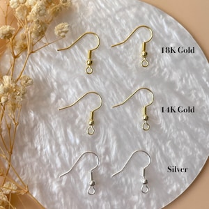 Op de afbeelding: Drie paar metalen oorbelhaakjes gerangschikt in rijen. Het bovenste paar is gelabeld 18K Gold, het middelste paar 14K Gold en het onderste paar Silver. Elke haak is voorzien van een klein kraaltje en een oogje voor het bevestigen van onderdelen.