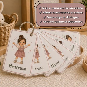 May include: Emotion flashcards on a metal ring. Each card shows a cartoon girl and a French emotion label, including "Heureuse" (Happy) and "Triste" (Sad). The cards are designed to help children understand and name their feelings.
