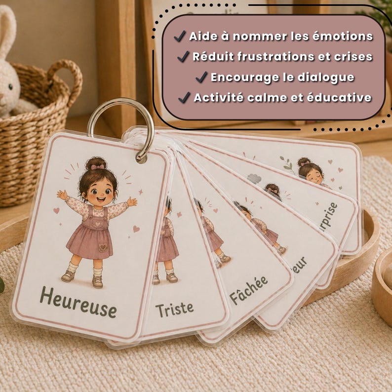 May include: Emotion flashcards on a metal ring. Each card shows a cartoon girl and a French emotion label, including "Heureuse" (Happy) and "Triste" (Sad). The cards are designed to help children understand and name their feelings.