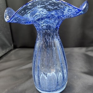 Peut inclure: Un vase en verre bleu cobalt doté d'un large bord ondulé et d'un corps bulbeux. Le verre se caractérise par une texture remplie de bulles sur toute sa surface, avec des indentations verticales courant le long des parois extérieures du vase.