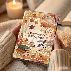 Könnte beinhalten: Eine transparente Handyhülle mit herbstlichen Aufklebern, darunter Blätter, Kürbisse und ein Pullover. Auf der Hülle steht "Sweater Weather Reading Season" und "Cozy Reader". Eine brennende Kerze und ein offenes Buch sind im Hintergrund.