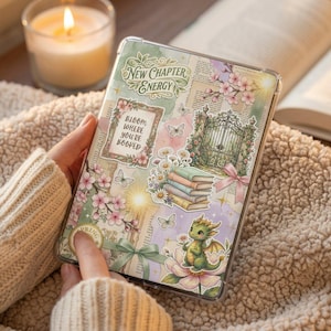 Könnte beinhalten: Eine dekorative Tablet-Hülle mit floralem und Fantasy-Design. Die Hülle zeigt den Text "New Chapter Energy" und "Bloom where you're rooted". Das Design umfasst einen Drachen, Bücher, Blumen und Schmetterlinge.