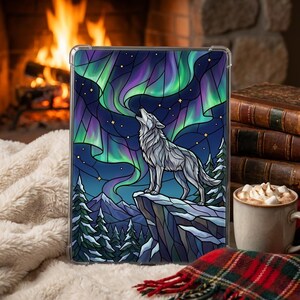 May include: A clear tablet case with a stained-glass style design. It depicts a howling wolf under the aurora borealis, with green, purple, and blue colours. The scene includes snow-covered trees and mountains.
