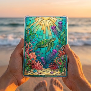 May include: A clear tablet case featuring a stained-glass design of an underwater scene. The design includes a green sea turtle, jellyfish, coral, and fish. The background shows a sunburst and the ocean.
