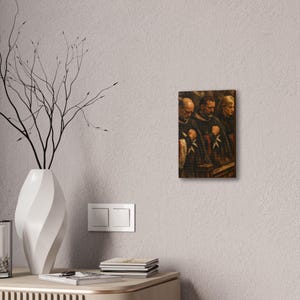 May include: A framed canvas print featuring a classical painting of three figures in dark robes, each with a white cross emblem. The figures are depicted with solemn expressions, suggesting a religious or historical theme. The artwork is mounted on a white wall.
