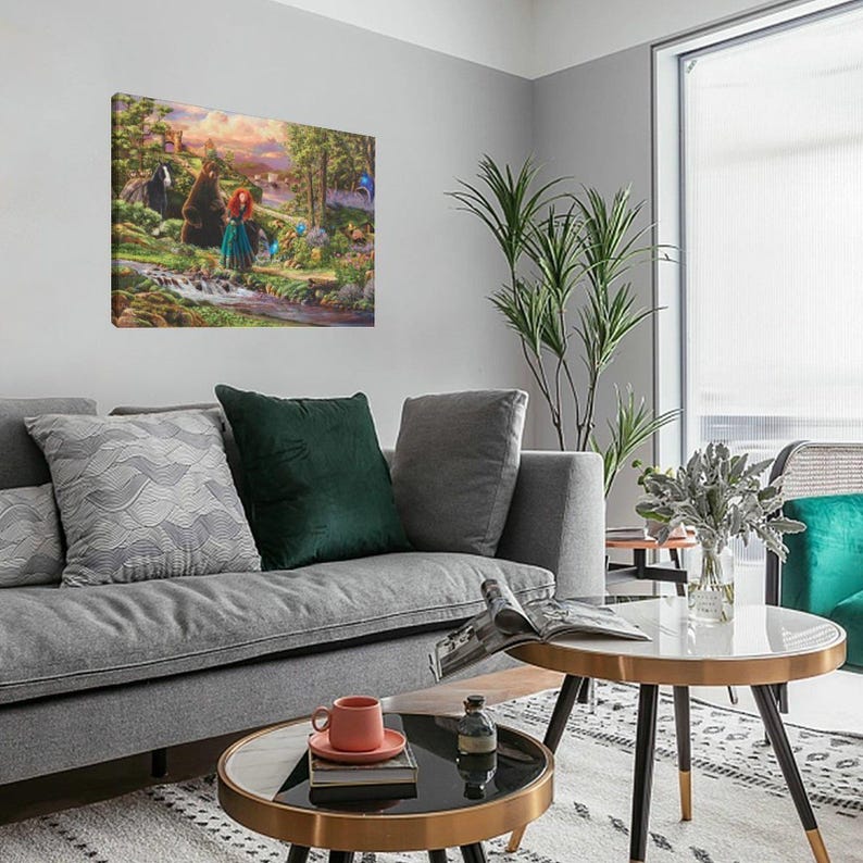 May include: A framed canvas art print depicting a scene from a fantasy movie. The artwork features a red-haired woman in a blue dress, a bear, and a forest setting with a stream. The print is displayed on a gray wall above a gray sofa.