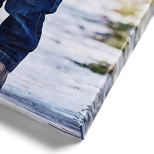 May include: Close-up of a canvas print with a wrapped edge. The canvas displays a blurred image with shades of blue, white, and green. The corner of the canvas is visible, showing the wrapped and stapled construction.