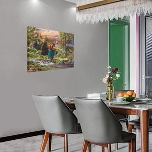 May include: A framed canvas art piece depicting a scene with a red-haired woman in a teal dress, a bear, and a forest setting with a stream. The artwork is mounted on a gray wall in a dining room setting.