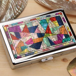 May include: A rectangular, silver-toned case with a colorful mosaic design on the lid. The mosaic features a geometric pattern of triangles and other shapes in various colors, including blue, green, pink, and orange. The case has a shiny, polished finish.