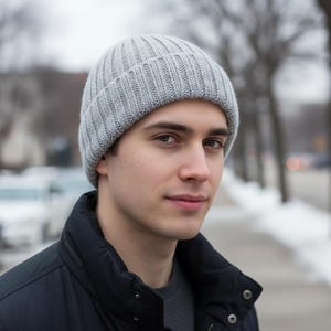 May include: A light gray ribbed knit beanie with a folded cuff. The hat features a vertical textured pattern throughout the fabric, providing a consistent knit structure that covers the crown of the head down to the ears.