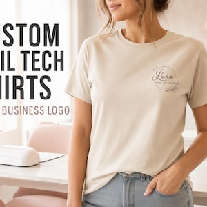 May include: A beige short-sleeved t-shirt featuring a small black circular logo on the left chest that reads Luna Nail Studio with botanical accents and stars. The text CUSTOM NAIL TECH SHIRTS YOUR BUSINESS LOGO is visible on the left side.