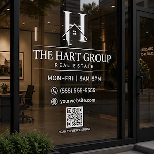 May include: Exterior view of a real estate office with a glass door displaying the company logo and contact information. The logo features a stylized 'H' with a house silhouette. Text includes 'THE HART GROUP REAL ESTATE' and a QR code.
