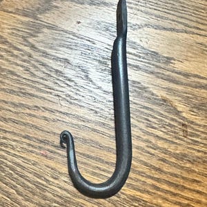 Puede incluir: Una taza de cerámica blanca con un asa negra y el texto "But First, Coffee" en negro, con una fuente de estilo manuscrito. La taza está sobre una superficie blanca.