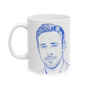 May include: A white ceramic mug featuring a blue line art illustration of a man with short hair and facial stubble. The portrait is centered on the front of the mug, showcasing detailed linework that captures the facial features.
