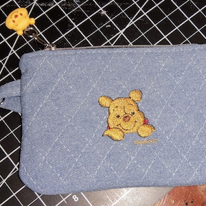 Bordado de Winnie the Pooh en un monedero pequeño, una bolsita, un bolso con cremallera... tela vaquera. Acolchado y luego bordado. Hecho a mano.