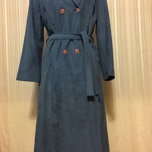 May include: A long, blue suede coat with a double-breasted closure, a belt, and brown buttons.