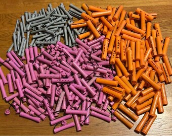 May include: A collection of hair rollers in various colors, including gray, pink, and orange. The rollers are cylindrical with small holes and are scattered across a wooden surface. The image showcases a variety of sizes and styles.