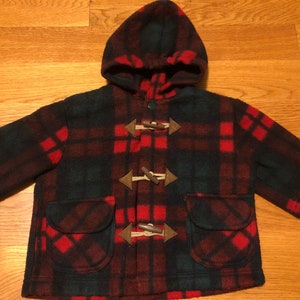 May include: Red and green plaid hooded jacket with brown toggle closures and two front pockets.