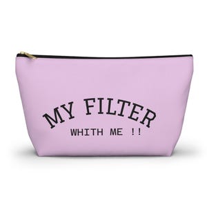 Puede incluir: Una bolsa con cremallera de color lila claro con el texto "MY FILTER WITH ME !!" en negro. La bolsa tiene una cremallera dorada y un tirador negro.