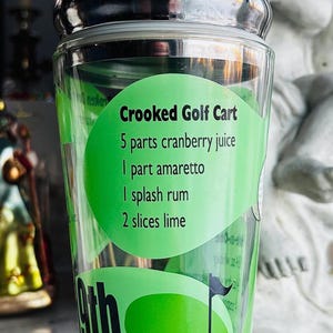 May include: A white ceramic mug with a black handle and the text "But First, Coffee" in a black, handwritten-style font. The mug is on a white surface.