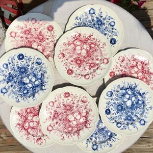 May include: Set of eight vintage floral patterned ceramic plates. The plates feature a white background with blue and pink floral designs. The plates have a scalloped edge.