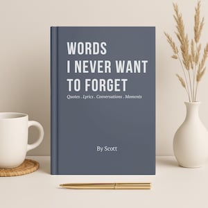 May include: A slate blue hardcover journal with white text that reads WORDS I NEVER WANT TO FORGET, Quotes . Lyrics . Conversations . Moments, and By Scott. The book is positioned upright with a gold pen placed horizontally in front of it.