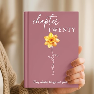 May include: A dusty rose hardcover book featuring the white text chapter TWENTY at the top. A yellow daffodil illustration sits in the center with the name emily written in white script below it. The text Every chapter brings new grow is at the bottom.