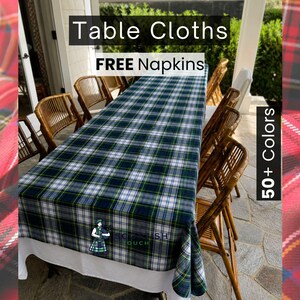 May include: A green, blue, and white plaid tablecloth covers a long table set with wooden chairs. The image includes the text "Table Cloths" and "FREE Napkins". The tablecloth has a white border and the text "Scottish Touch".