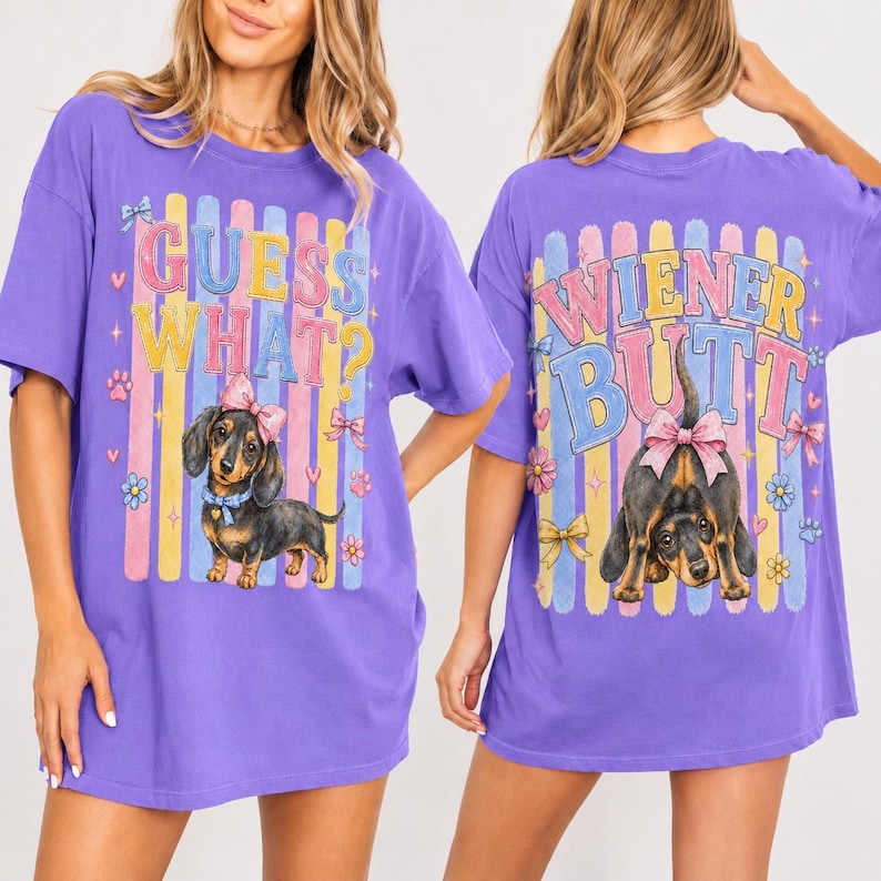 May include: A purple t-shirt with a dachshund graphic and the text "GUESS WHAT?" on the front. The back of the shirt features a dachshund graphic and the text "WIENER BUTT". The shirt has a relaxed fit.