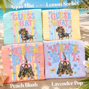 May include: Four colorful dachshund-themed throw pillows. Two pillows say "Guess What?" with a dachshund illustration. The other two pillows say "Wiener Butt" with a dachshund illustration. Colors include aqua, yellow, peach, and lavender.