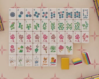 May include: A set of white mahjong tiles featuring colorful illustrations of tennis balls, dog bones, paw prints, flowers, and dogs. The tiles include numerical markings, text labels like East, South, North, and Joker, and some blank yellow tiles.