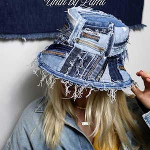 Può includere: Un cappello a secchiello in denim patchwork con bordi sfilacciati. Il cappello è realizzato con varie tonalità di denim blu e presenta un'etichetta "PULL&BEAR". Il testo "Unik by Lumi" è visibile sullo sfondo.