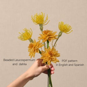 Puede incluir: Un ramo de flores de cuentas hechas a mano con Leucospermum amarillos y dalias de color naranja dorado sobre tallos verdes. El texto en la imagen dice: Beaded Leucospermum and dahlia, PDF pattern in English and Spanish. Flores de cuentas.