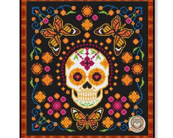 May include: Cross-stitch design featuring a sugar skull with orange and yellow accents, surrounded by butterflies and floral patterns on a black background. The design is framed in a wooden border.