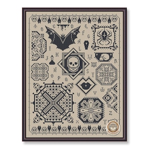 May include: Framed cross-stitch sampler with a Halloween theme. The design features a bat, spider, skull, and other spooky motifs in black on a tan background. The sampler is enclosed in a dark brown frame.