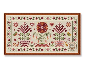 May include: A rectangular cross-stitch embroidery pattern on cream fabric featuring a central large flower, two potted plants, hearts, stars, birds, and butterflies in shades of red, green, and yellow, all enclosed within a brown wooden frame.