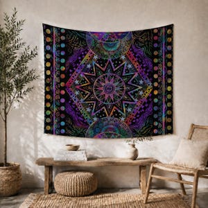 Puede incluir: Un tapiz de pared rectangular con fondo negro y un diseño celestial vibrante y multicolor. El patrón incluye una estrella central, lunas crecientes y bordes geométricos con motivos circulares en tonos morados, azules y naranjas.
