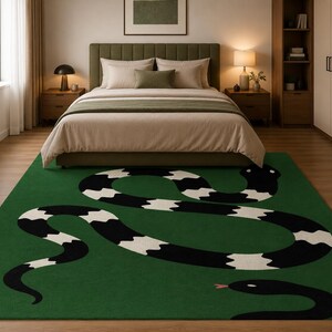Peut inclure: Un tapis rectangulaire au fond vert profond orné d'un grand motif de serpent stylisé. Le serpent présente un motif répétitif de bandes noires et blanches sur tout le corps, une tête entièrement noire et une petite langue fourchue rose visible.