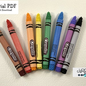 Op de afbeelding: Een set van acht miniatuur Crayola-kleurpotloden, elk met een andere kleur en een parelkraalpunt. De kleuren zijn bruin, rood, oranje, geel, groen, blauw, paars en zwart. De kleurpotloden zijn in een halve cirkel op een wit oppervlak gerangschikt. De tekst "Crayola" is zichtbaar op elk kleurpotlood.