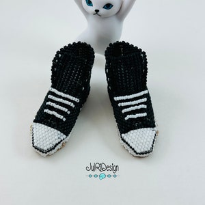 Peut inclure: Une paire de baskets en perles noires et blanches avec des lacets blancs. Les baskets sont assez petites pour s'adapter &agrave; une poup&eacute;e ou une figurine.